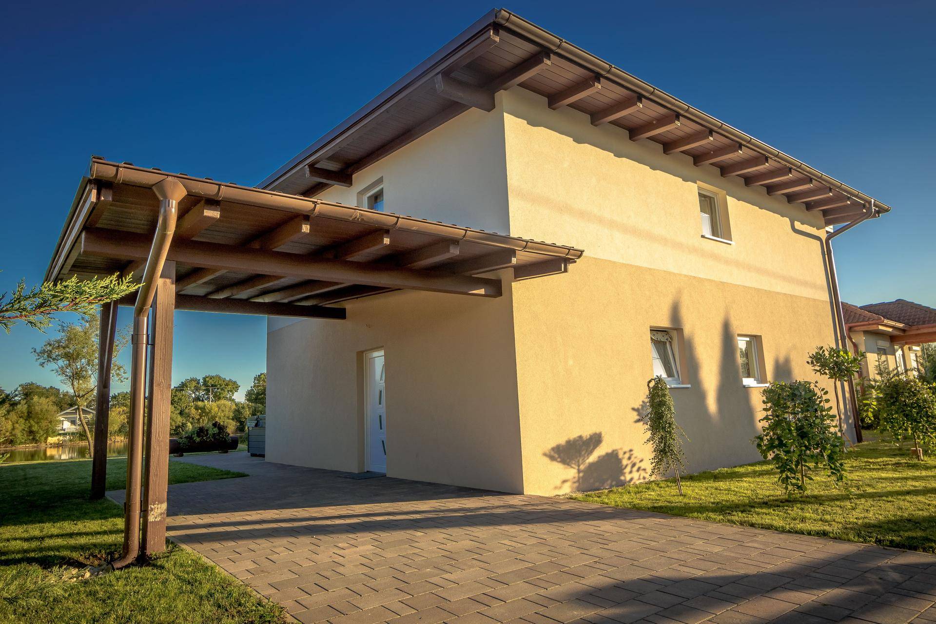 Seitenansicht des Hauses mit Carport und gepflastertem Zugangsbereich.