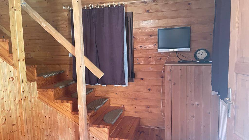 Rustikale Holztreppe führt in das Obergeschoss, mit einem kleinen Fernseher an der Wand.