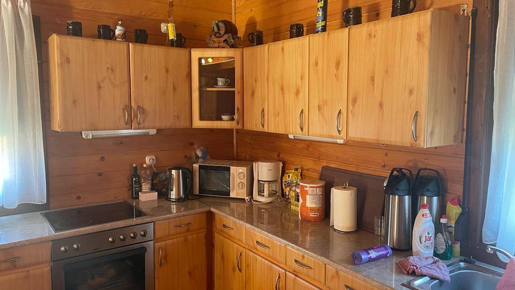 Funktionale Holzküche mit Einbauschränken, Kochfeld, Backofen und Mikrowelle.
