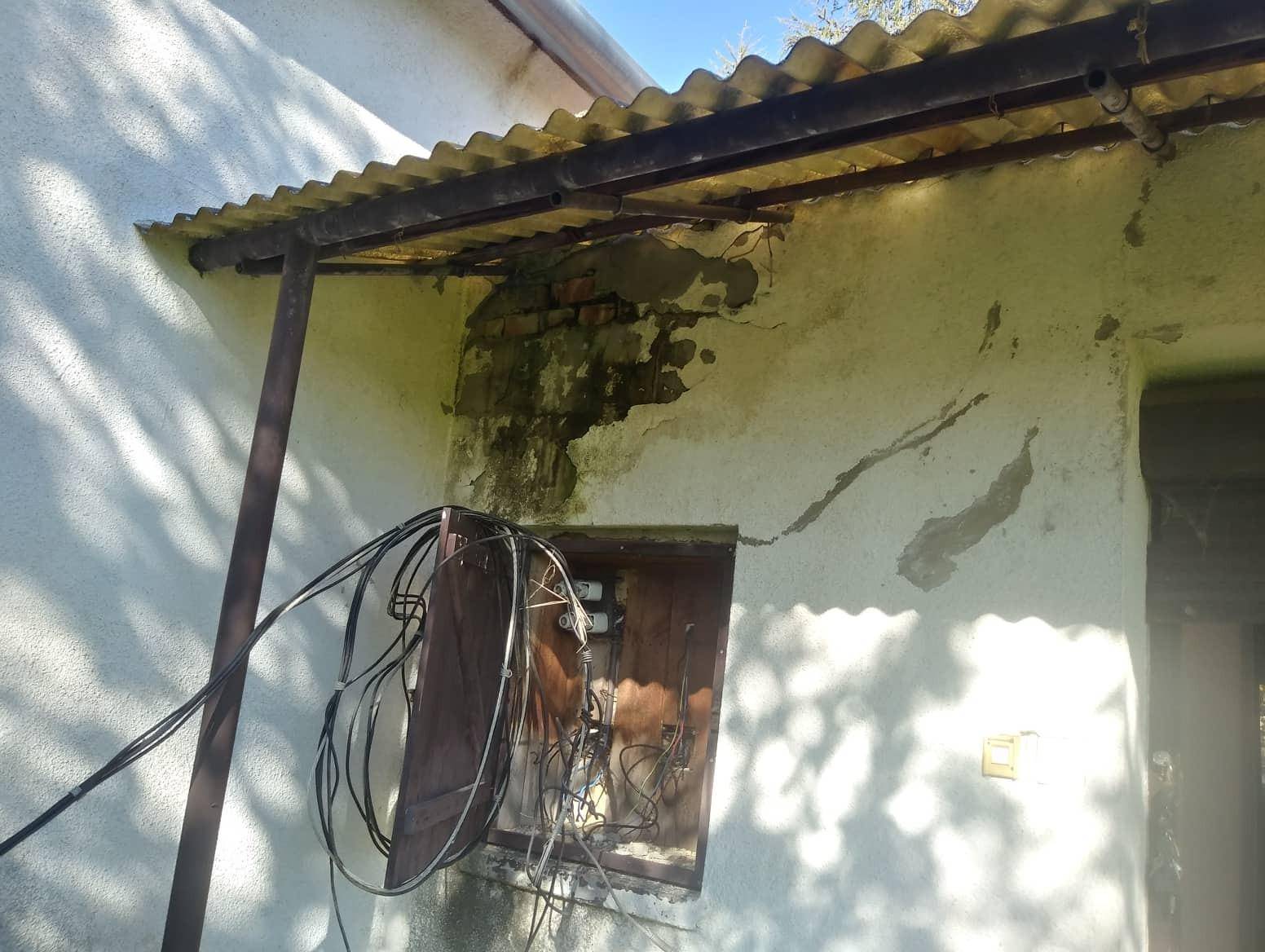 Beschädigte Hauswand mit freiliegenden Kabeln und undichtem Dachüberstand, deutliche Mängel sichtbar.