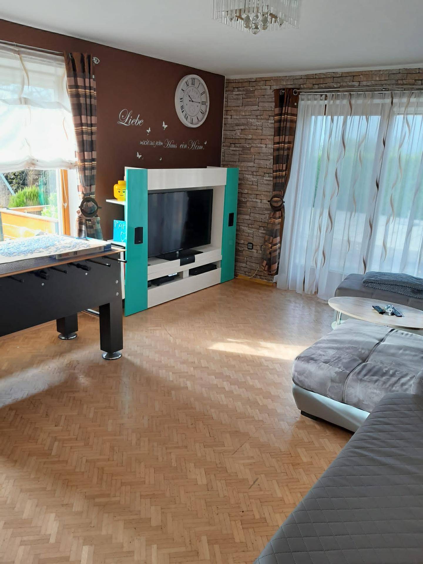 Geräumiges Wohnzimmer mit Laminatboden, Sofa und Zugang zur Terrasse.