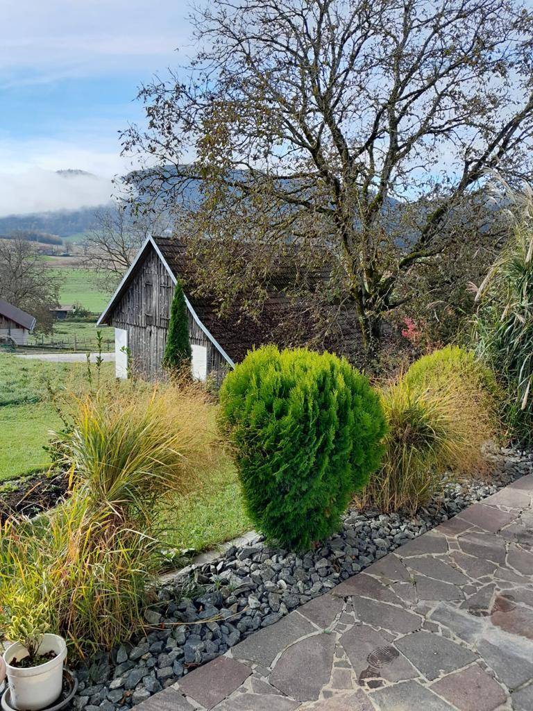 Gartenbereich mit Ziergräsern, Bäumen und weitem Blick auf die Landschaft.