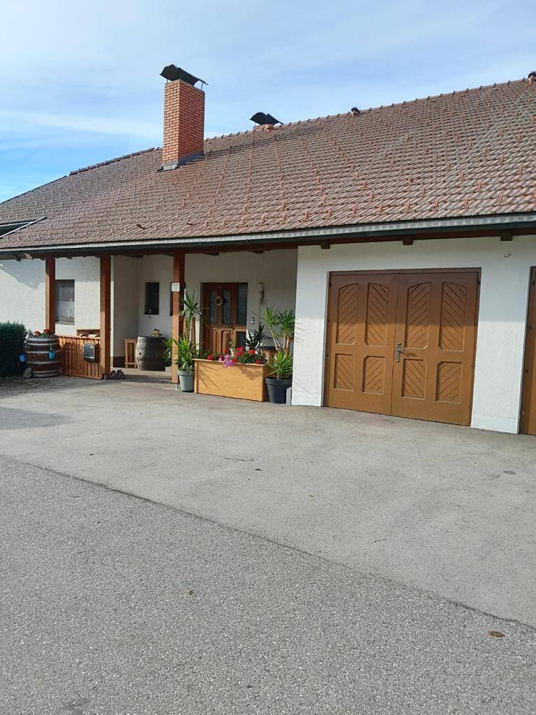 Vorderansicht des Hauses mit Garagentoren, überdachtem Eingang und Ziegeldach.
