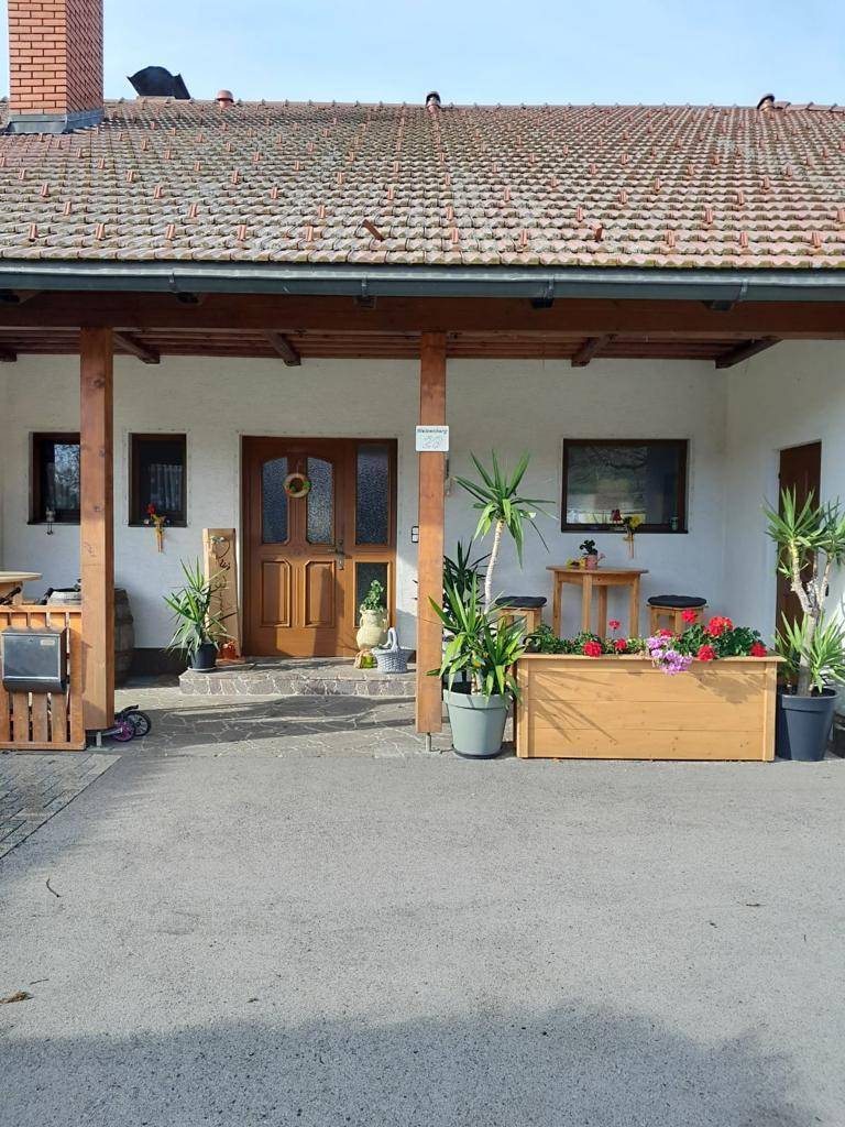 Überdachter Eingangsbereich des Hauses mit Holzsäulen und dekorativen Pflanzen.