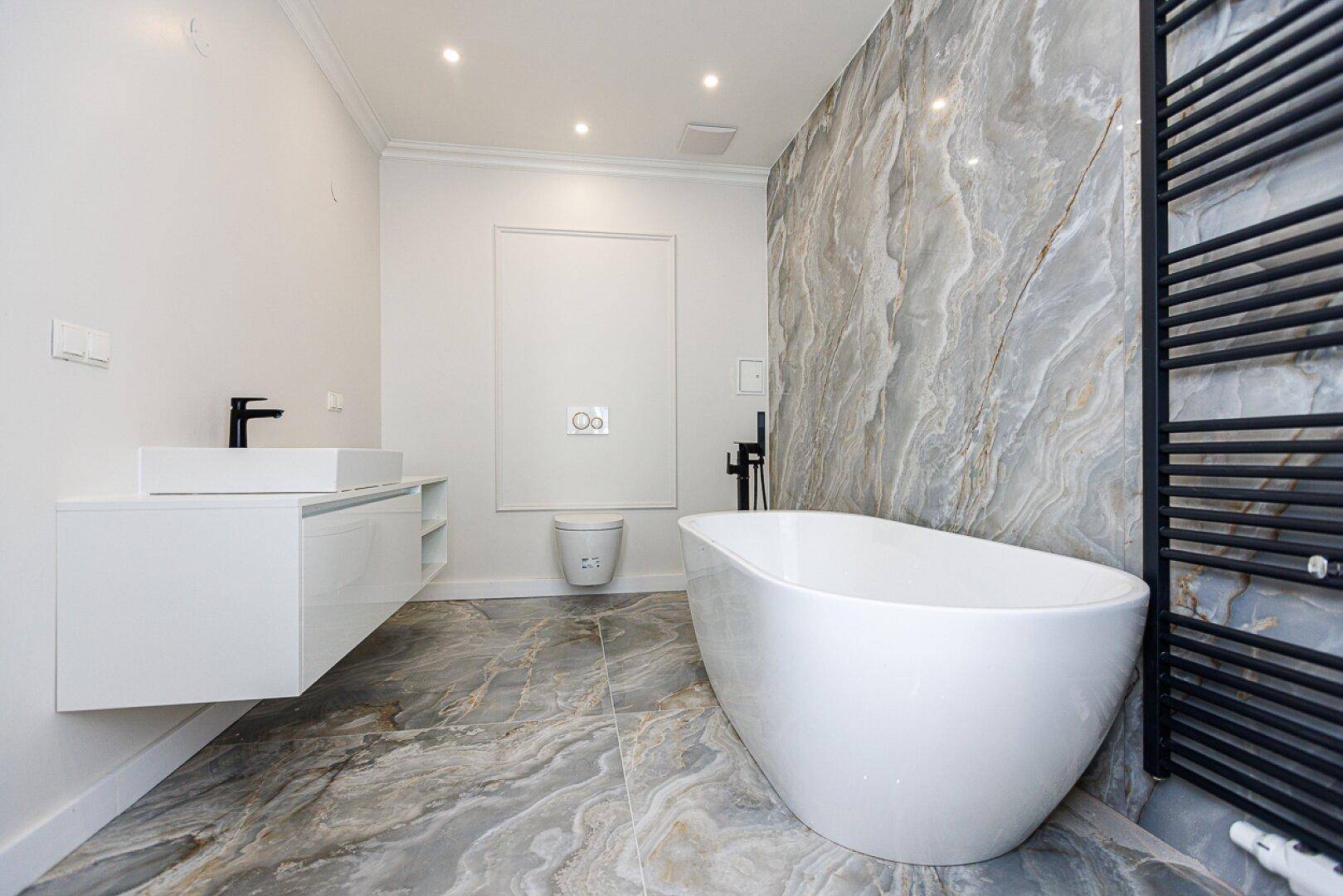 Luxuriöses Badezimmer mit freistehender Badewanne, schwebendem Waschtisch und eleganten Marmorfliesen.