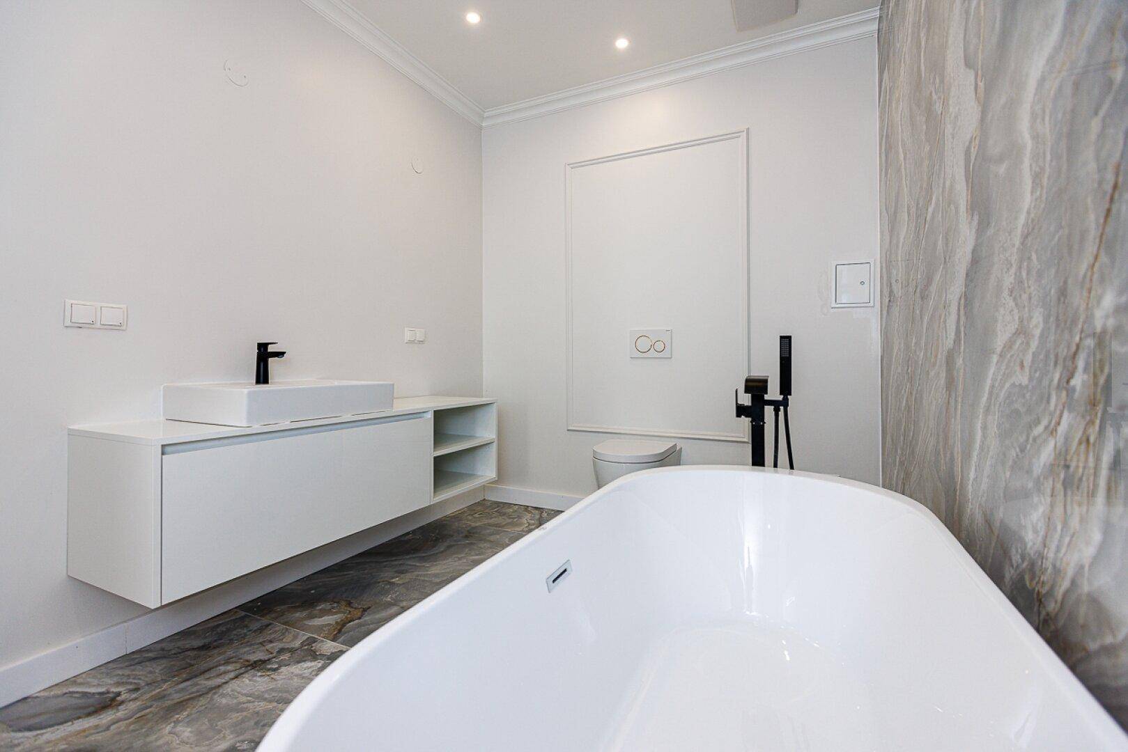 Elegantes Badezimmer mit freistehender Badewanne, modernem Waschtisch und Marmorfliesen.