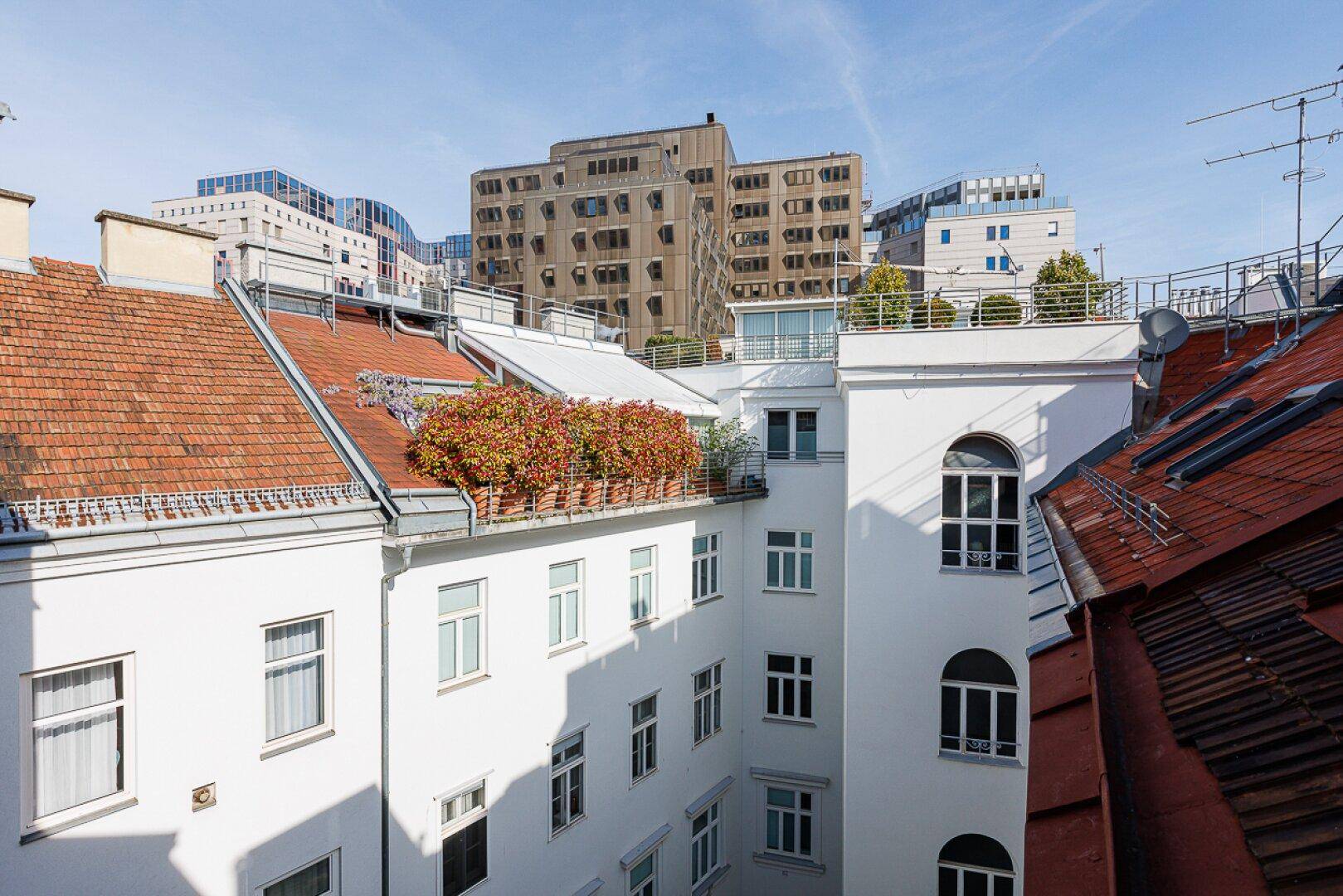 Blick in einen ruhigen Innenhof mit begrünten Dächern und umliegenden Gebäuden.
