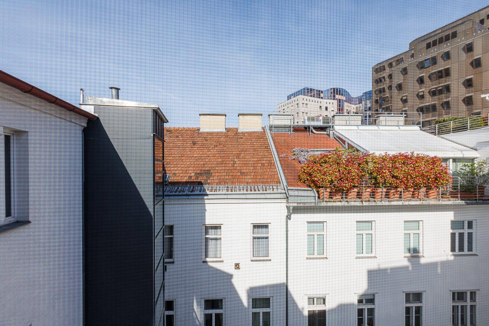 Blick in einen ruhigen Innenhof mit begrünten Dächern und umliegenden Gebäuden.