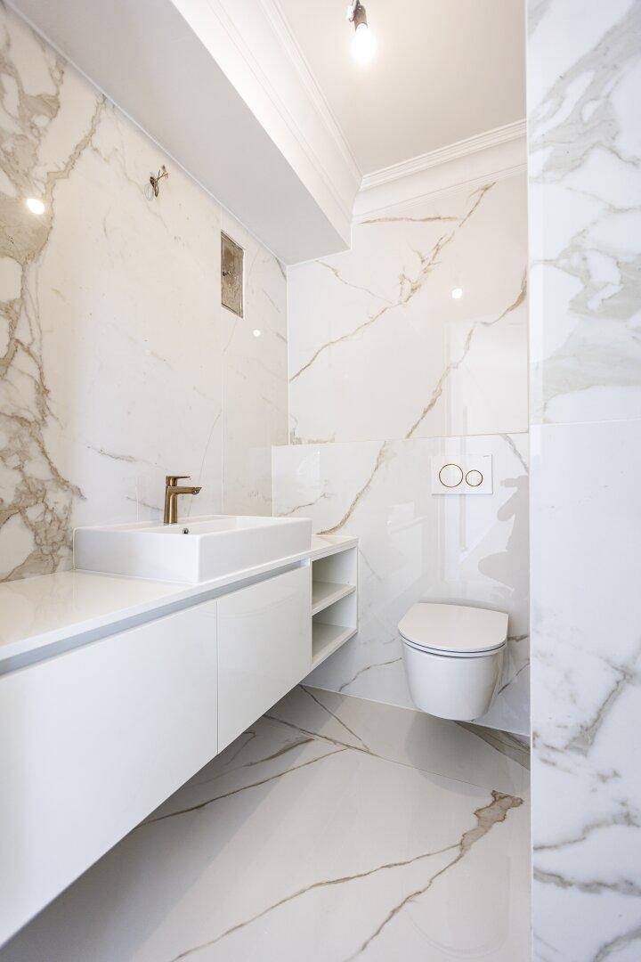 Elegantes Gäste-WC mit Marmoroptik-Fliesen, modernem Waschtisch und wandhängendem WC.