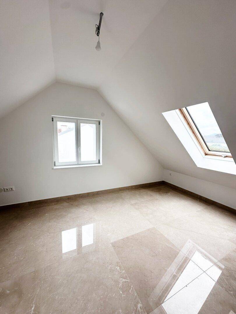 Helles Schlafzimmer im Dachgeschoss mit glänzenden Fliesen und Dachfenster.