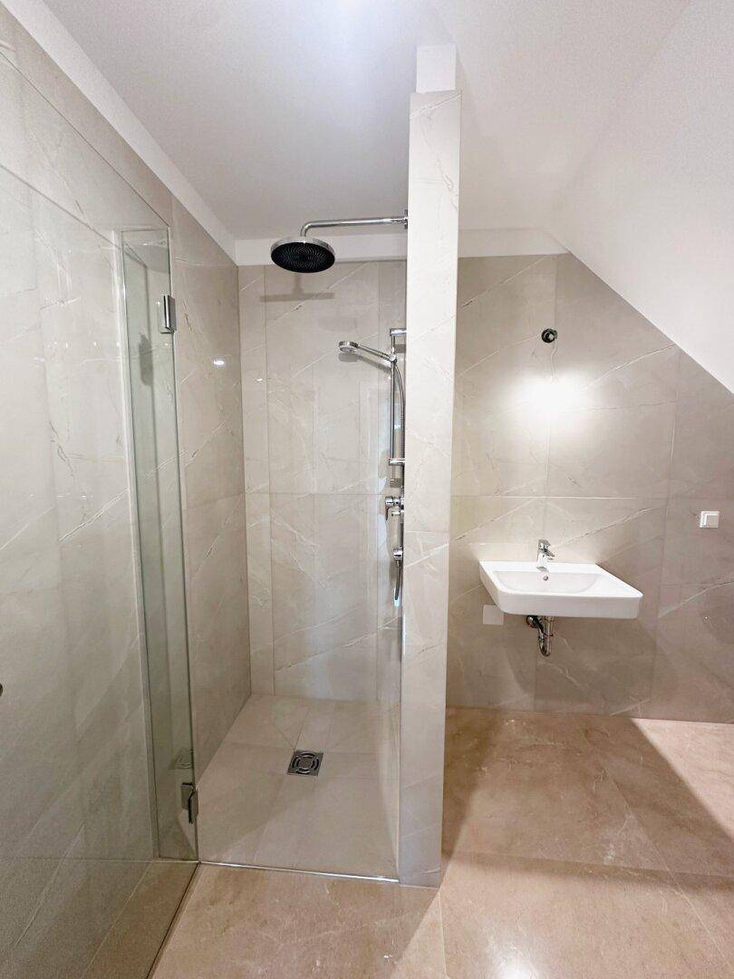 Modernes Badezimmer im Dachgeschoss mit begehbarer Dusche, Regendusche und Wandwaschbecken.