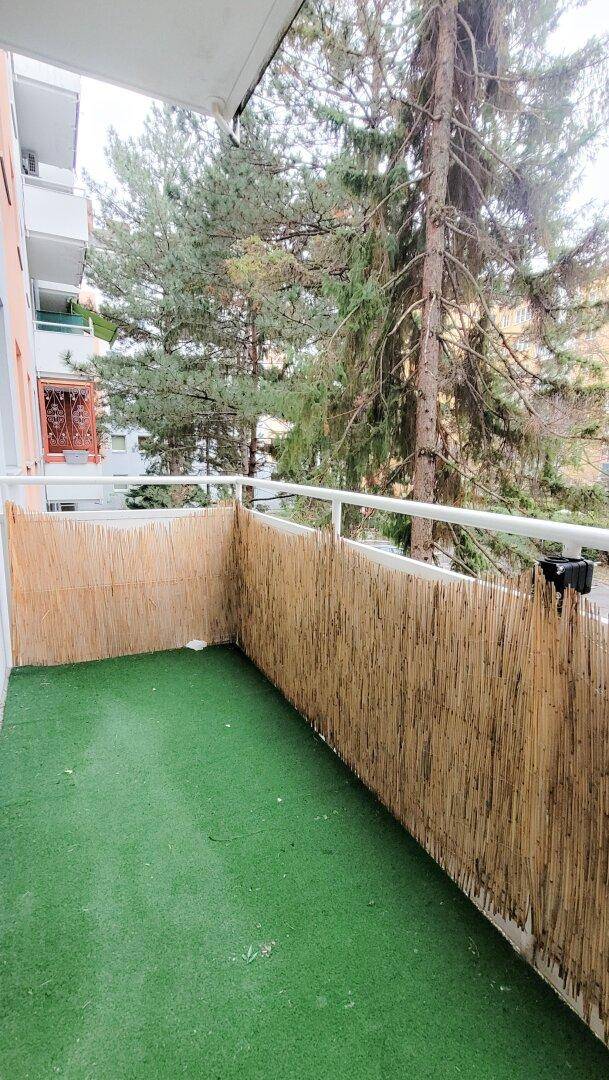 Gemütlicher Balkon mit Kunstrasen und Sichtschutz, umgeben von Bäumen für Privatsphäre.