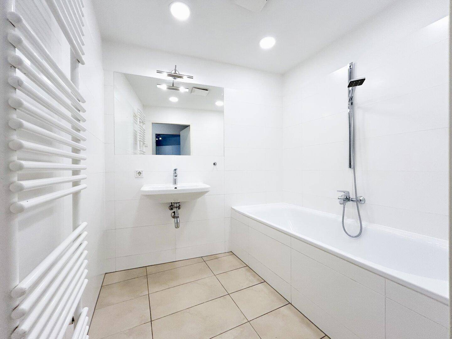 Modernes Badezimmer mit Badewanne, Dusche, Waschbecken und beheiztem Handtuchhalter.
