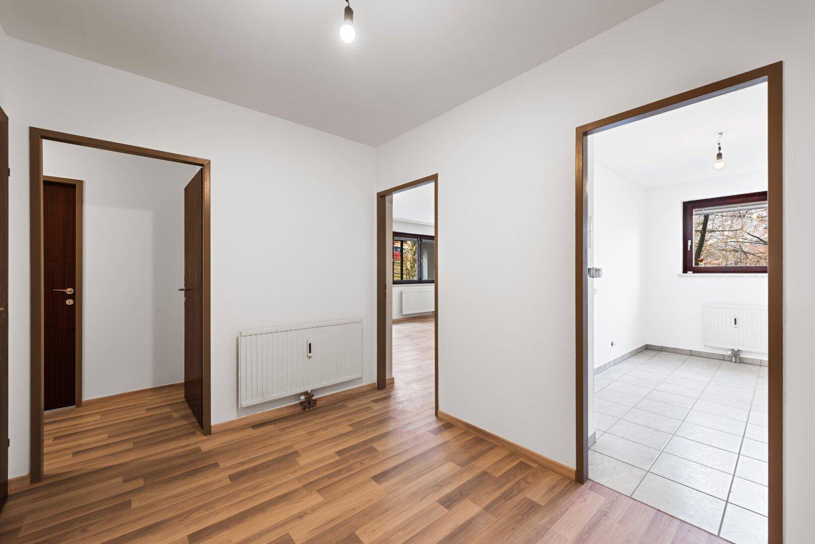 Heller Flur mit Laminatboden und mehreren Türen, die zu den angrenzenden Zimmern führen.