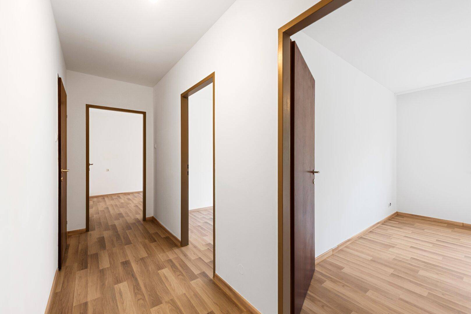 Langer Flur mit Laminatboden und Holztüren, der die verschiedenen Räume der Wohnung verbindet.