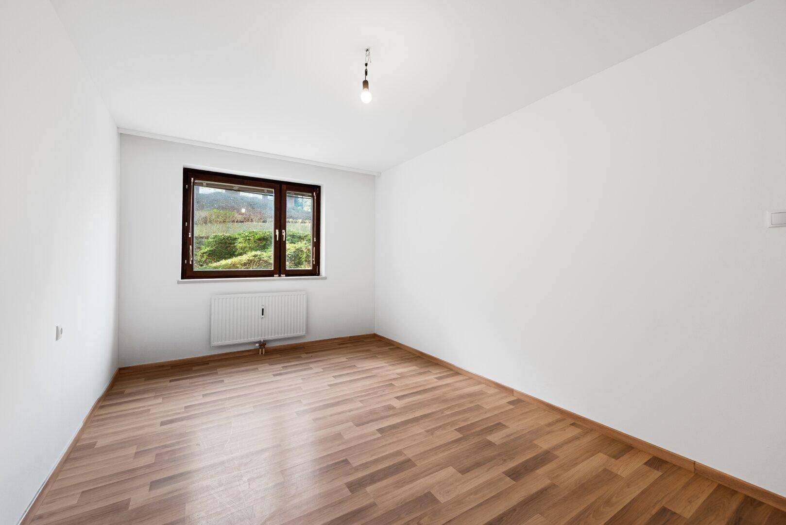 Geräumiges Zimmer mit Laminatboden und Fenster, das für eine helle und freundliche Atmosphäre sorgt.