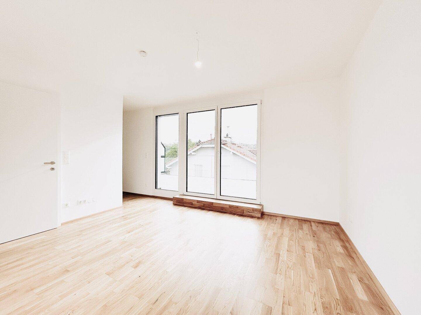 Helles Schlafzimmer mit Parkettboden und großen Fenstern, die viel Licht spenden und Ausblick bieten.