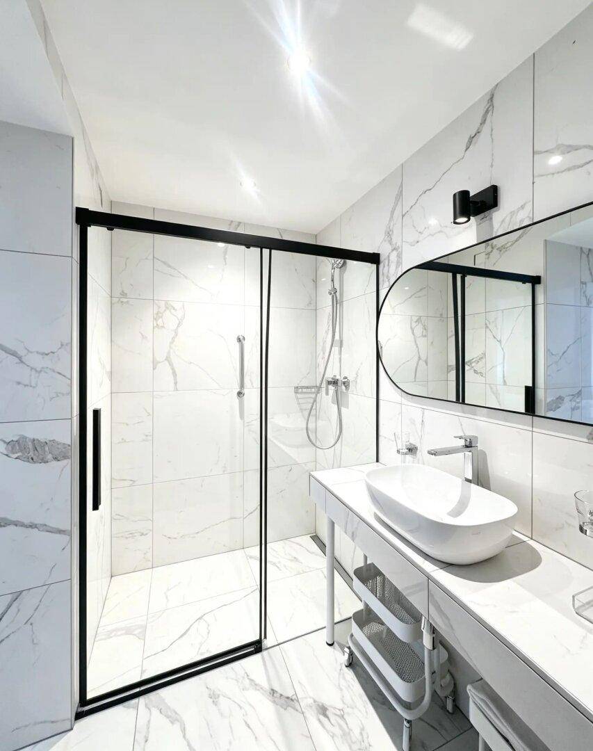 Modernes Badezimmer mit großformatigen Marmorfliesen, begehbarer Dusche und elegantem Waschbecken.