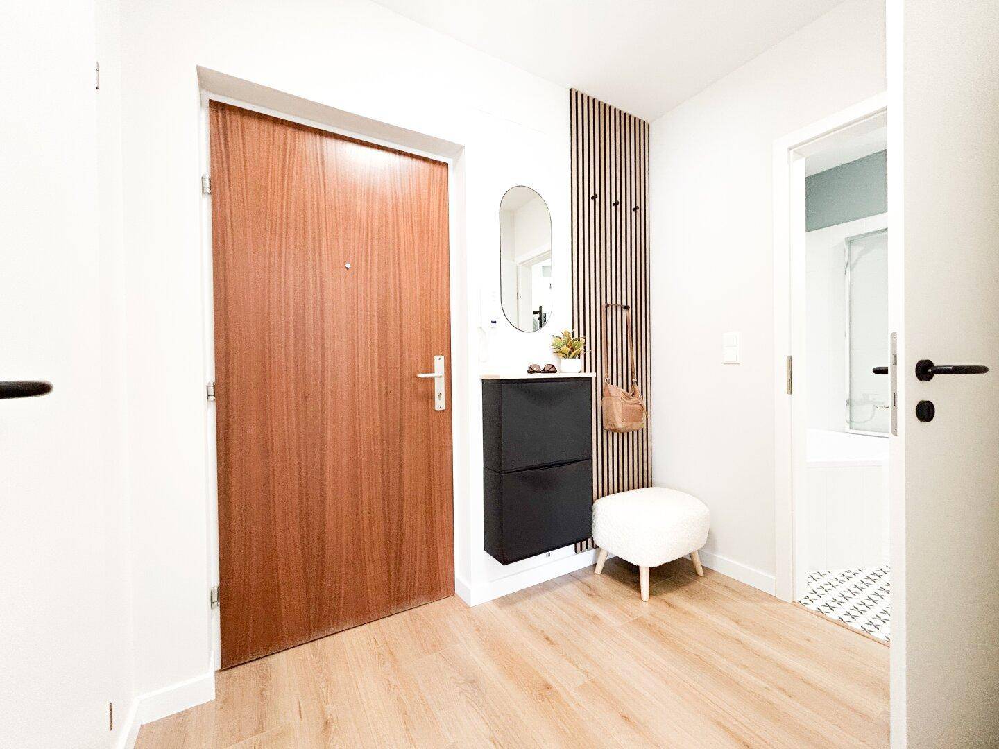 Eingangsbereich mit Holztür, Schuhschrank und dekorativer Holzlamellenwand.