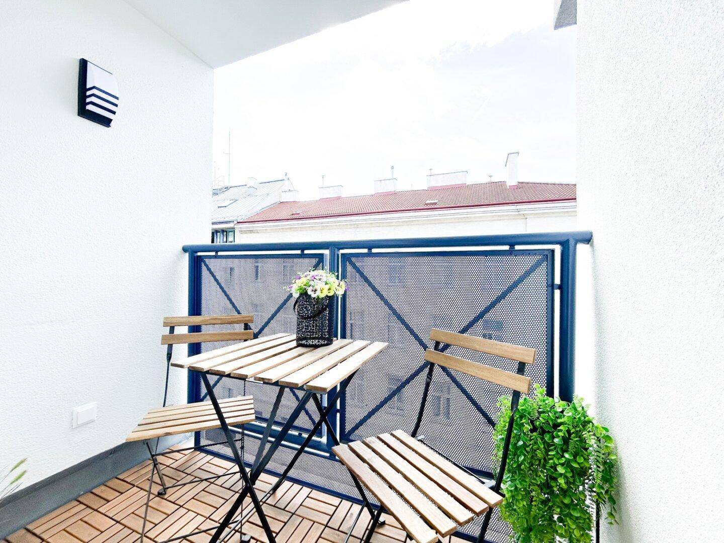 Kleiner Balkon mit Holzbodenfliesen und Sitzgelegenheiten, ideal für entspannte Stunden.