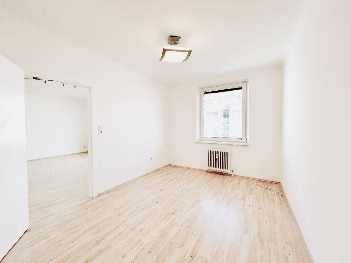 Weiteres leeres Zimmer mit Laminatboden und Fenster, ideal als Schlaf- oder Arbeitszimmer.