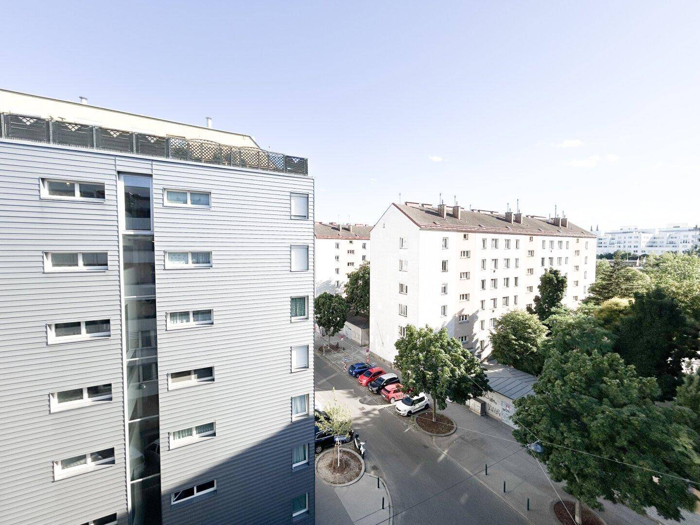 Blick auf moderne und traditionelle Wohngebäude in einer städtischen Umgebung mit Bäumen.