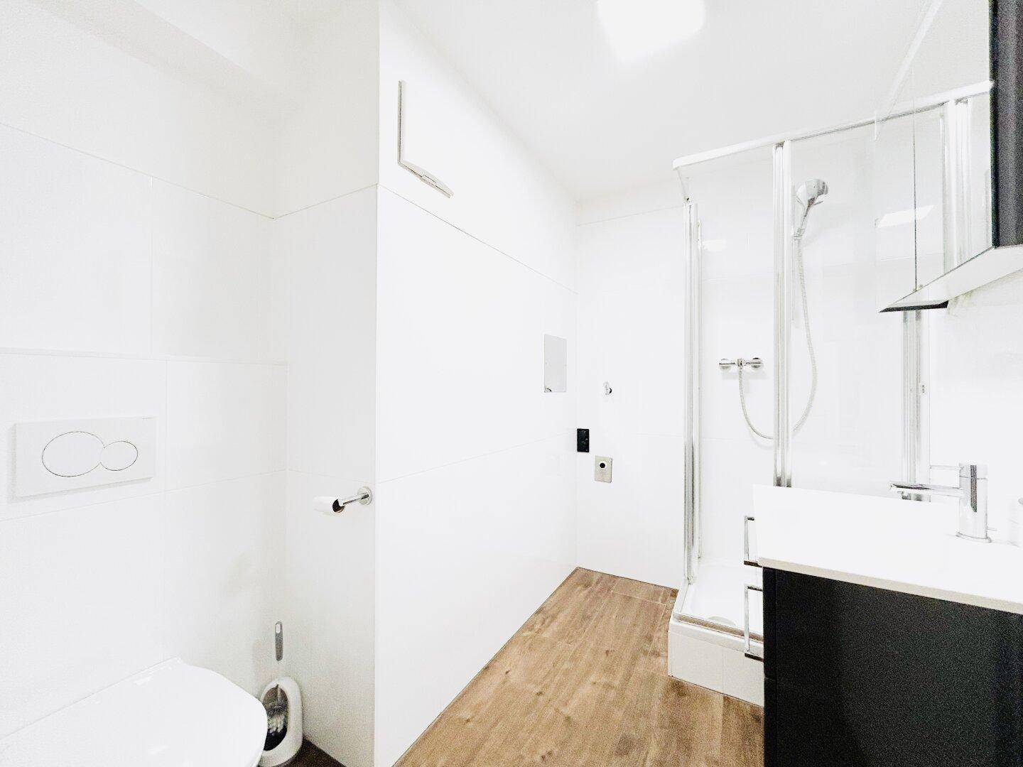 Modernes Badezimmer mit Duschkabine und wandhängendem WC in minimalistischem Design.