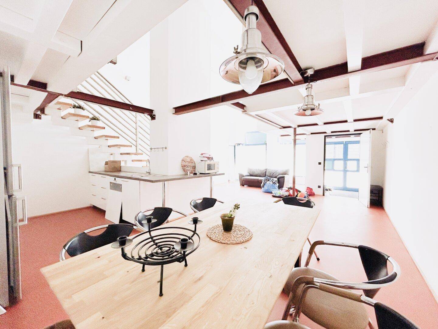 Geräumiger Essbereich mit Holztisch und offener Küche in einem hellen Loft-Ambiente.