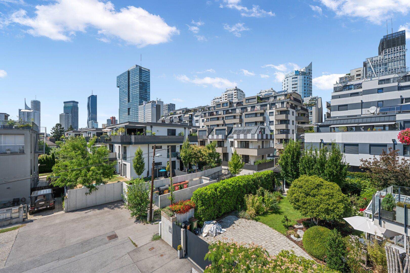 Blick auf eine moderne Wohngegend mit viel Grün und der Skyline im Hintergrund.