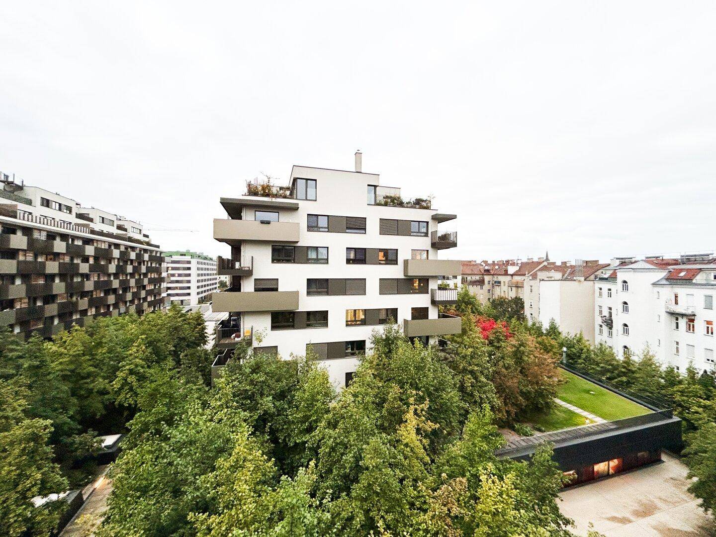 Panoramablick auf ein modernes Wohngebäude mit Terrassen und umliegenden Grünflächen.