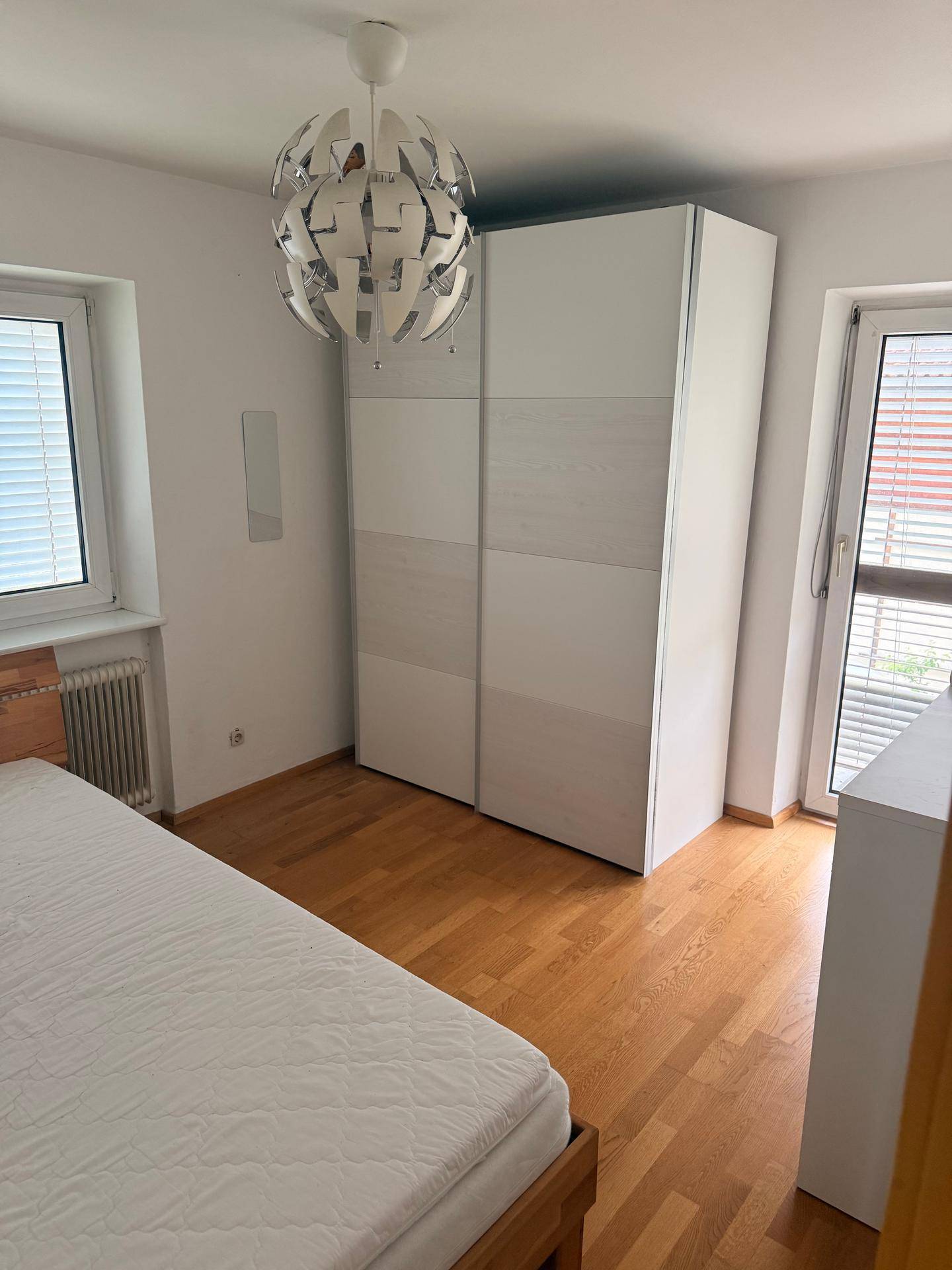 Geräumiges Schlafzimmer mit Holzbett, großem Kleiderschrank und moderner Deckenleuchte.