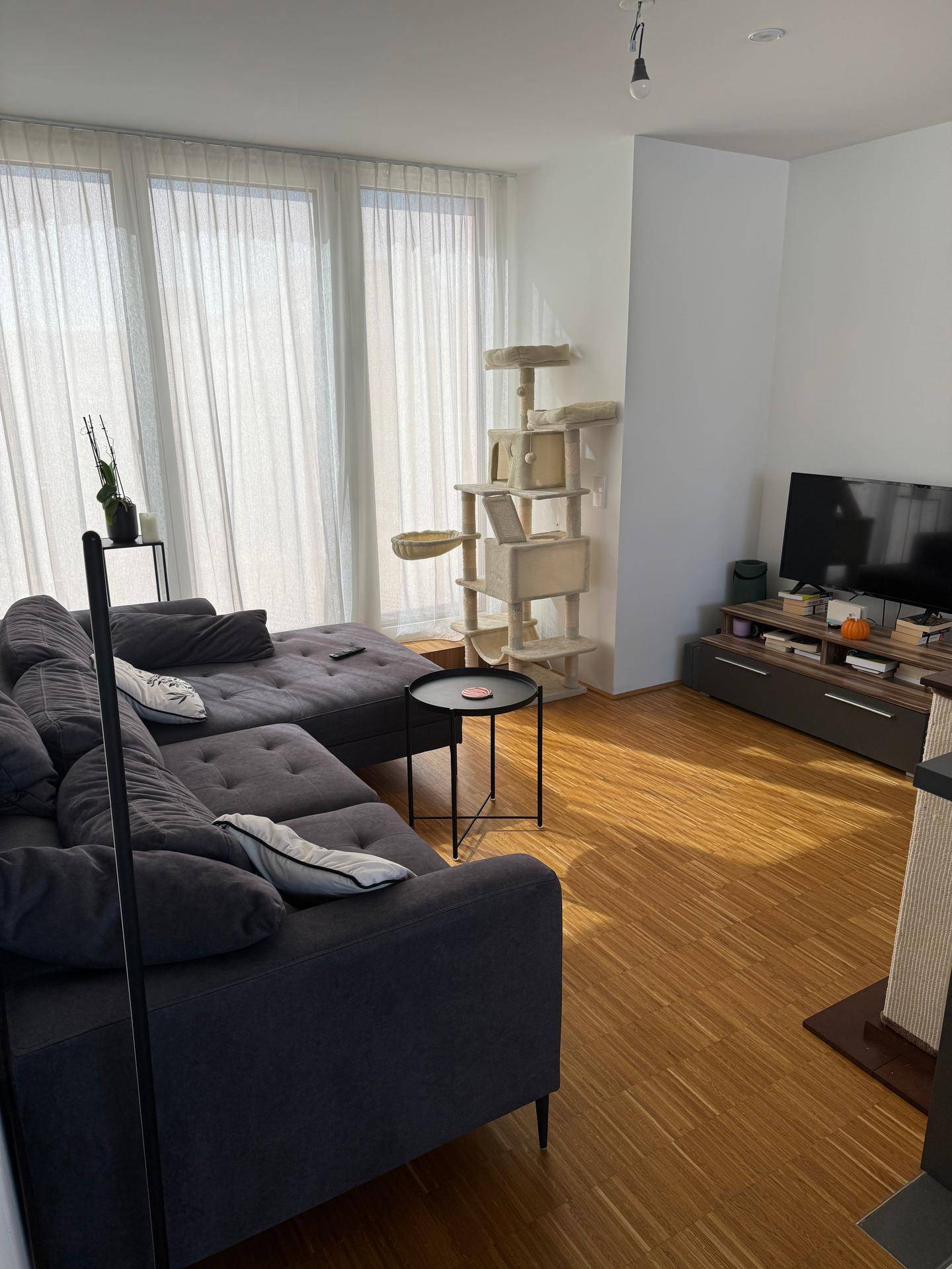 Geräumiges Wohnzimmer mit großem Ecksofa, TV-Möbeln und hellen Fenstern.