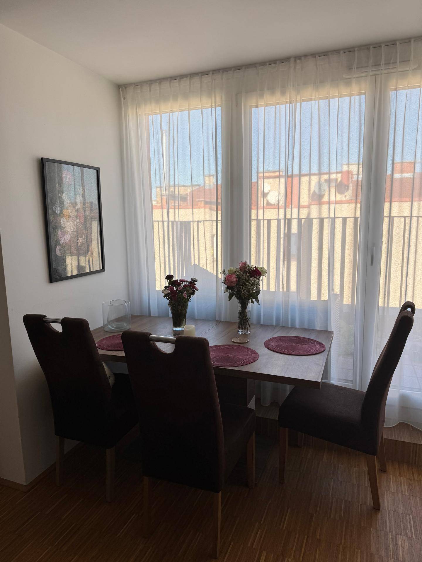 Gemütlicher Essbereich mit Holztisch, Stühlen und großen Fenstern mit viel Tageslicht.