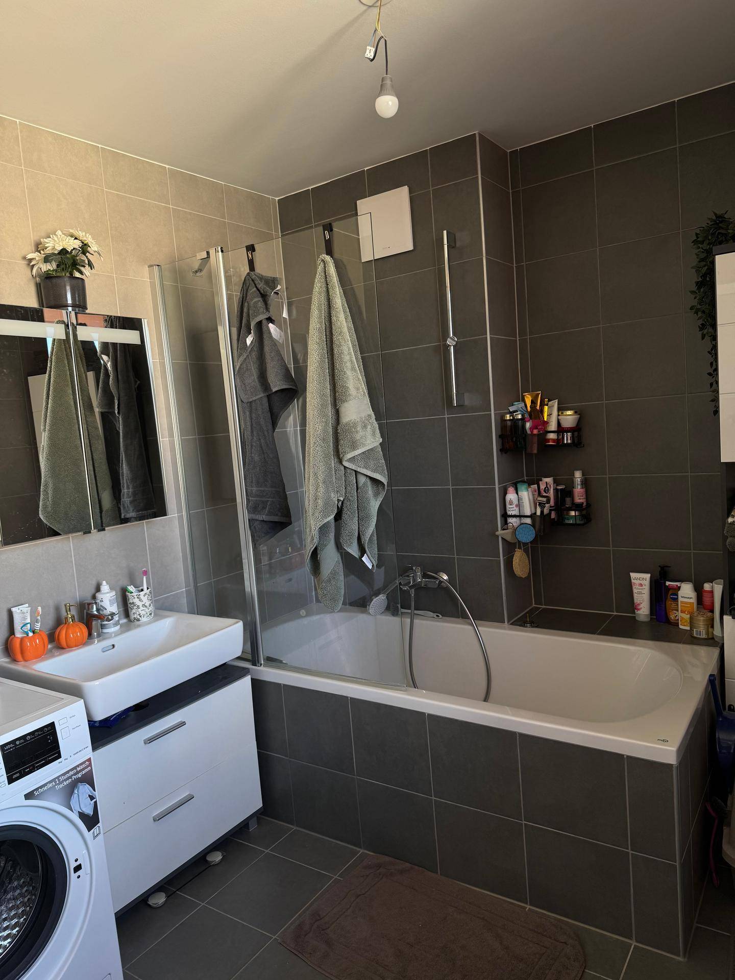 Modernes Badezimmer mit Badewanne, Duschabtrennung, Waschbecken und Waschmaschine.