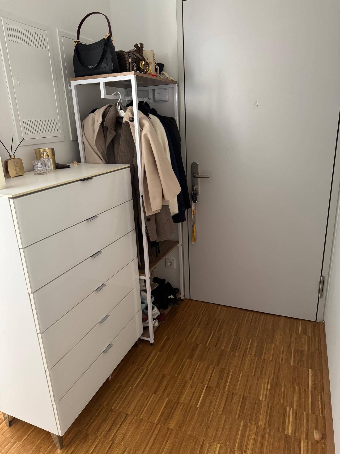 Heller Eingangsbereich mit Holzboden, Kommode und Garderobe.