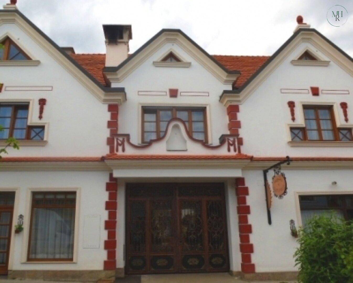 Traditionelle Hausfassade mit weißen Wänden, roten Akzenten und einem verzierten Eingangstor.