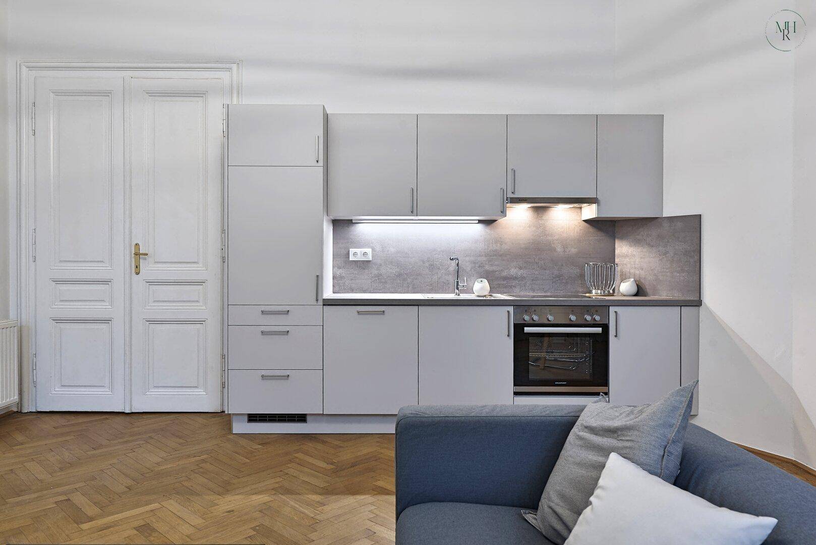 Moderne Küchenzeile in Grau mit integriertem Backofen und ausreichend Stauraum.