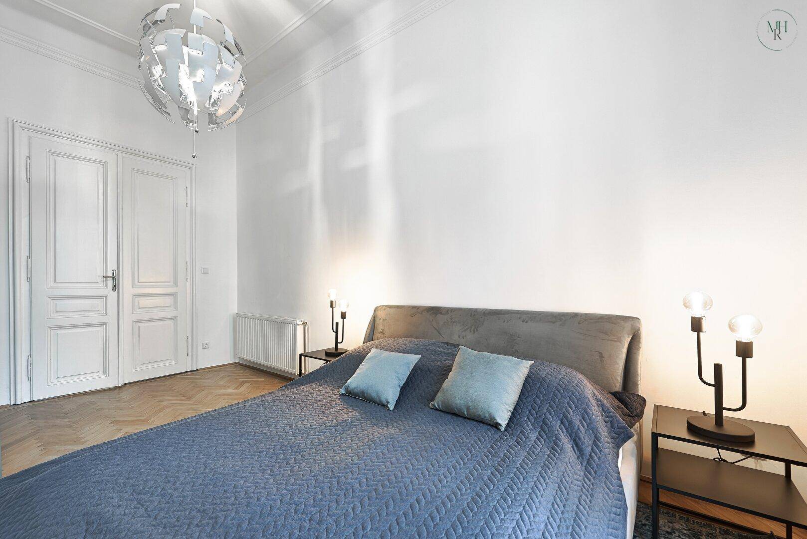 Geräumiges Schlafzimmer mit Doppelbett, Parkettboden und hohen Decken.