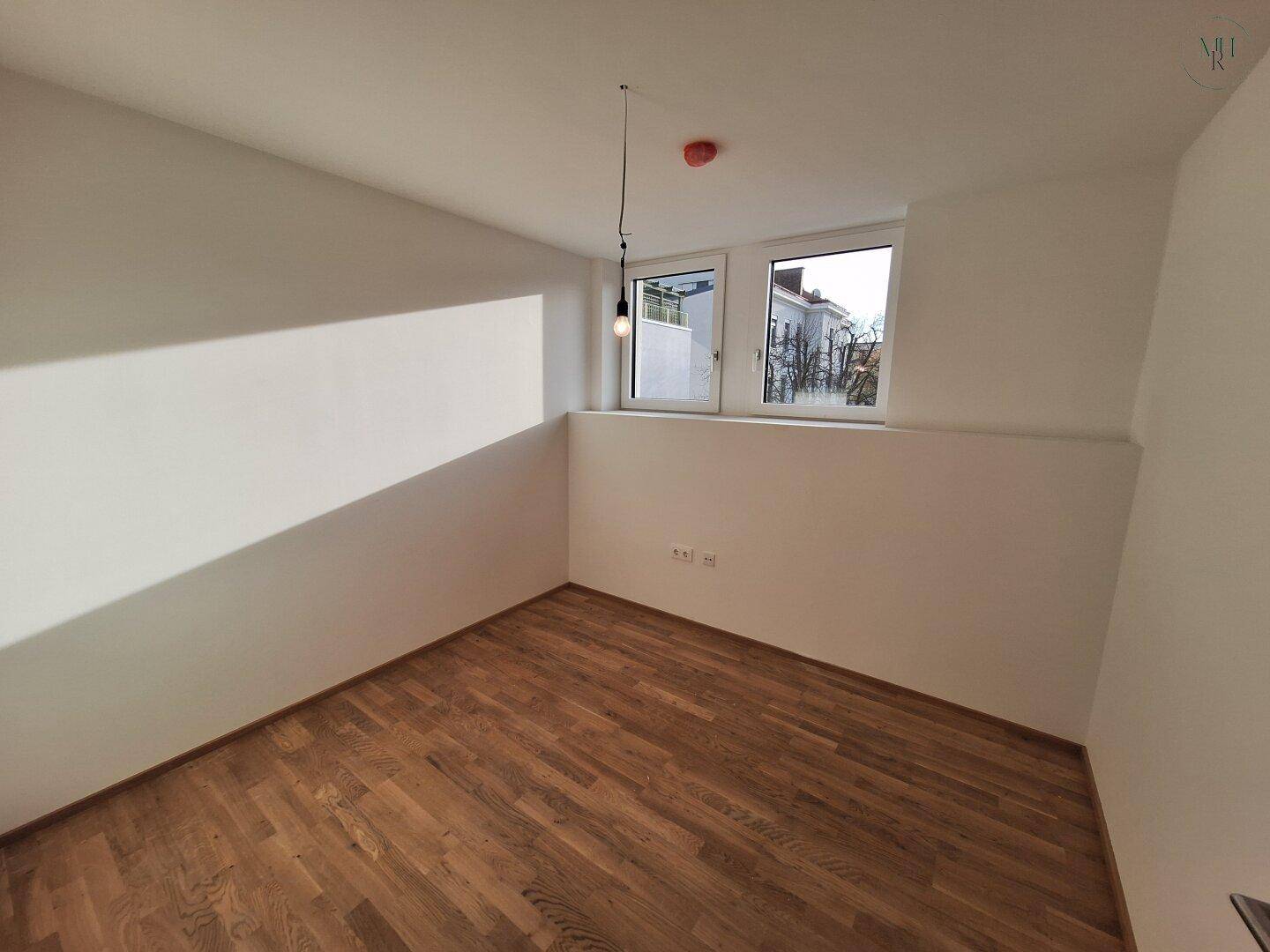 Geräumiges Schlafzimmer mit Holzboden und hellen Wänden, ideal für individuelle Gestaltung.