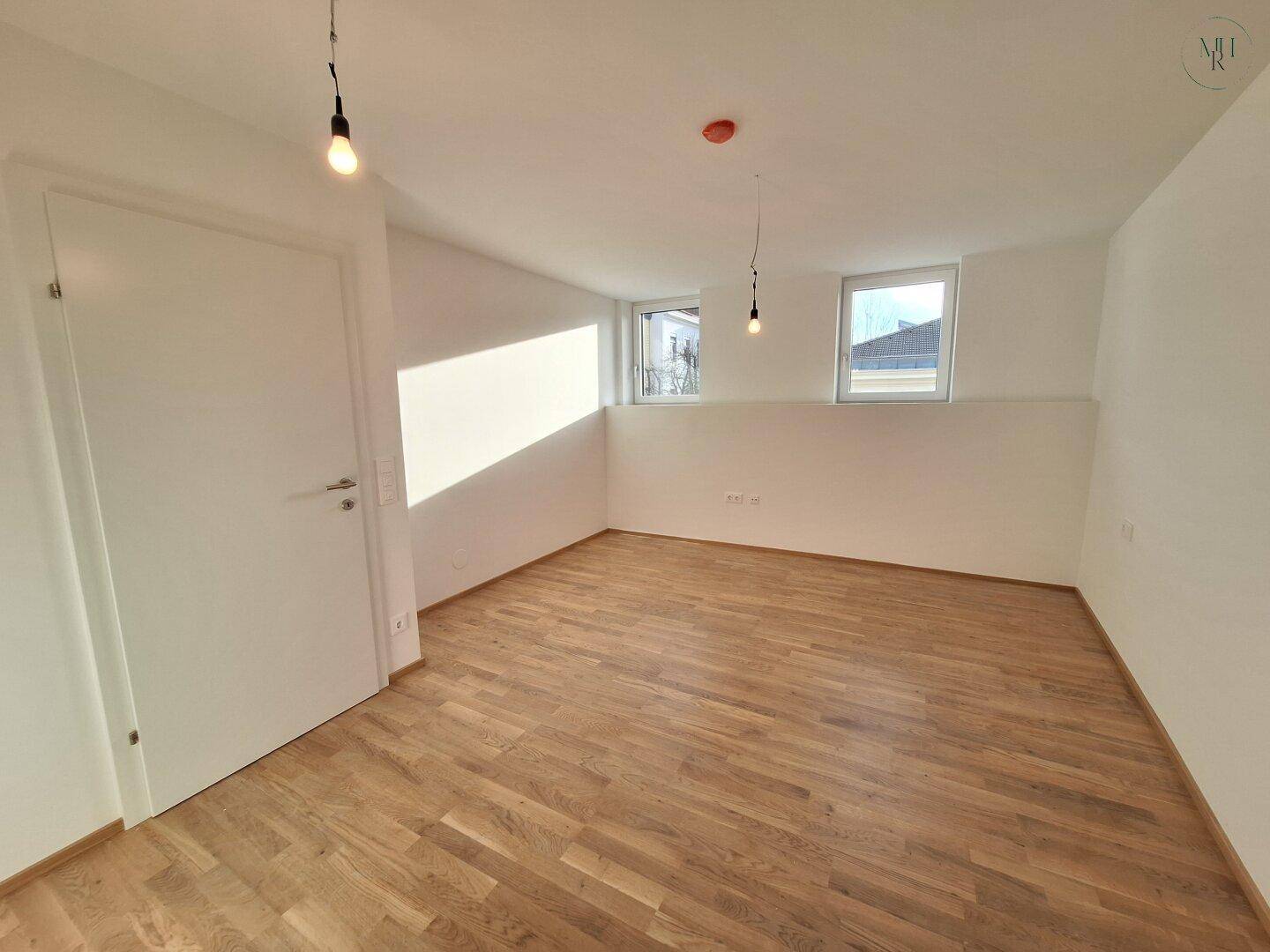 Helles Schlafzimmer mit Eichenparkett und zwei Fenstern für viel Tageslicht.