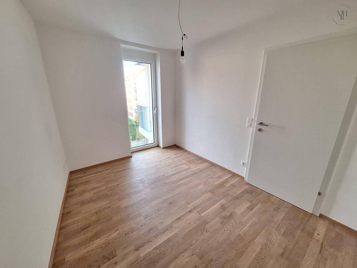 Helles Zimmer mit Eichenparkett und direktem Zugang zu einem Außenbereich.