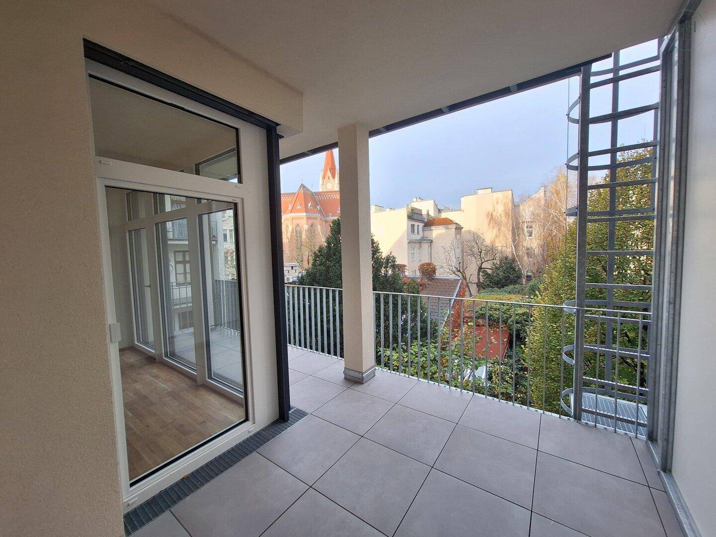 Großer Balkon mit Fliesenboden und Blick auf die Stadt und eine historische Kirche.