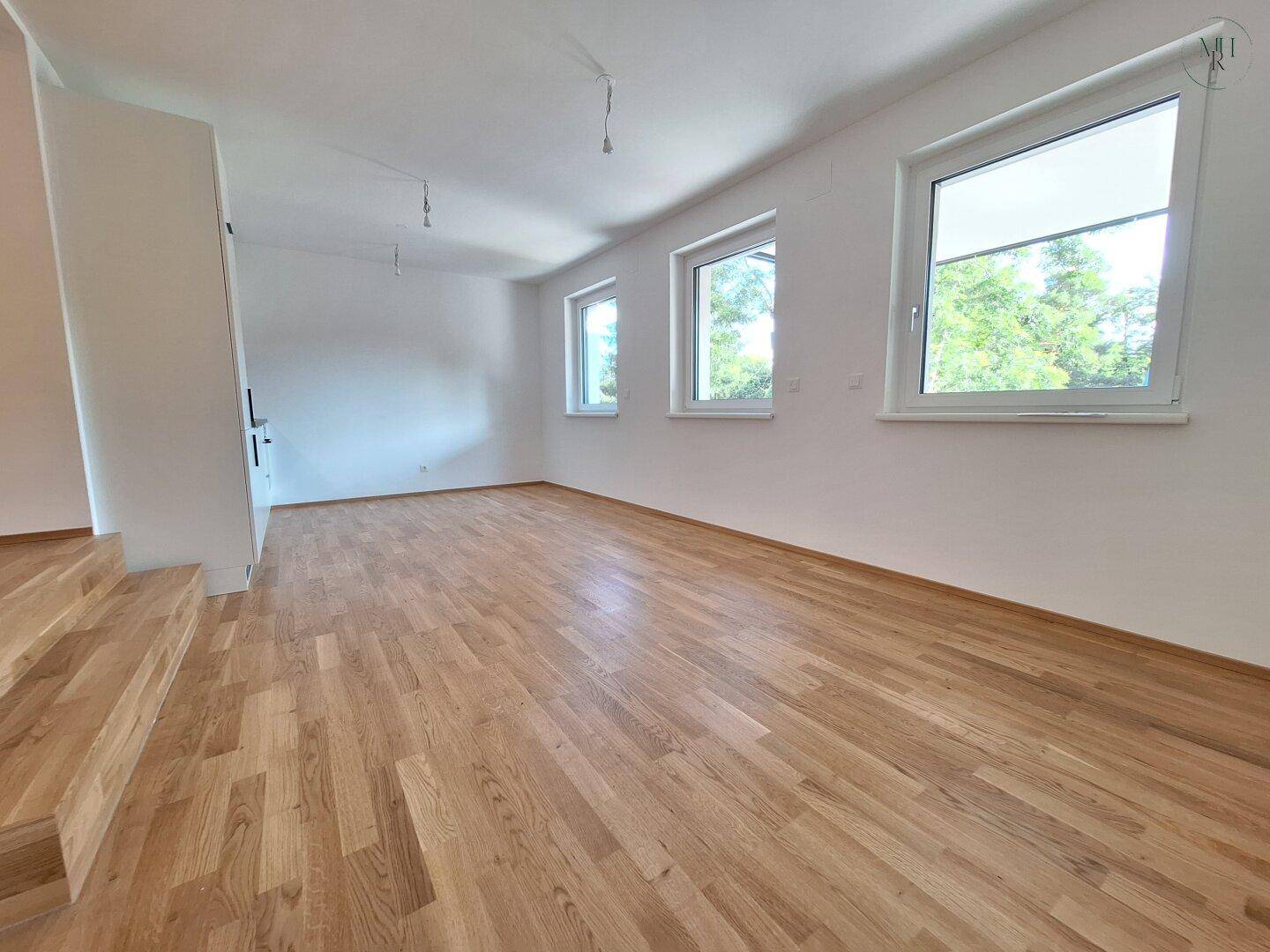 Heller Wohnraum mit neuem Eichenparkett und großen Fenstern, die viel Tageslicht hereinlassen.