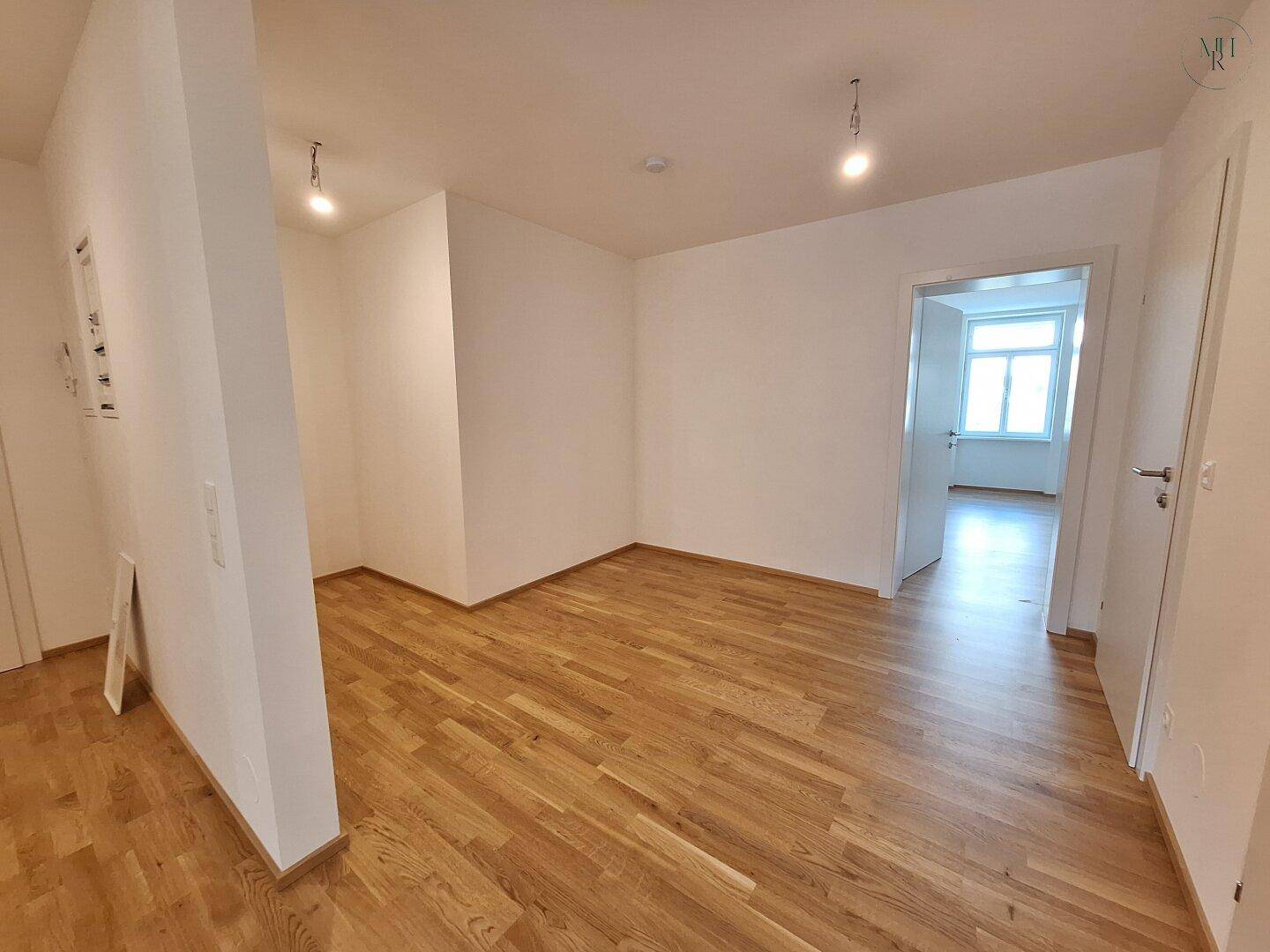 Offener Flurbereich mit Holzparkett und Zugang zu weiteren hellen Räumen der Wohnung.