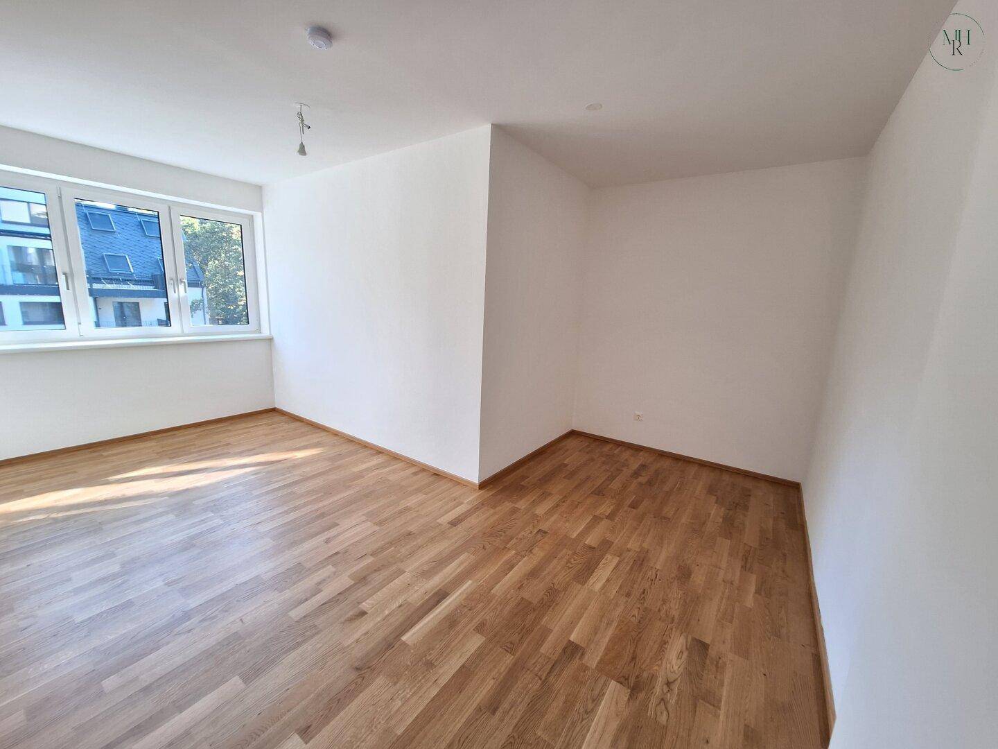 Geräumiges Schlafzimmer mit Parkettboden und Fensterblick auf die umliegende moderne Architektur.