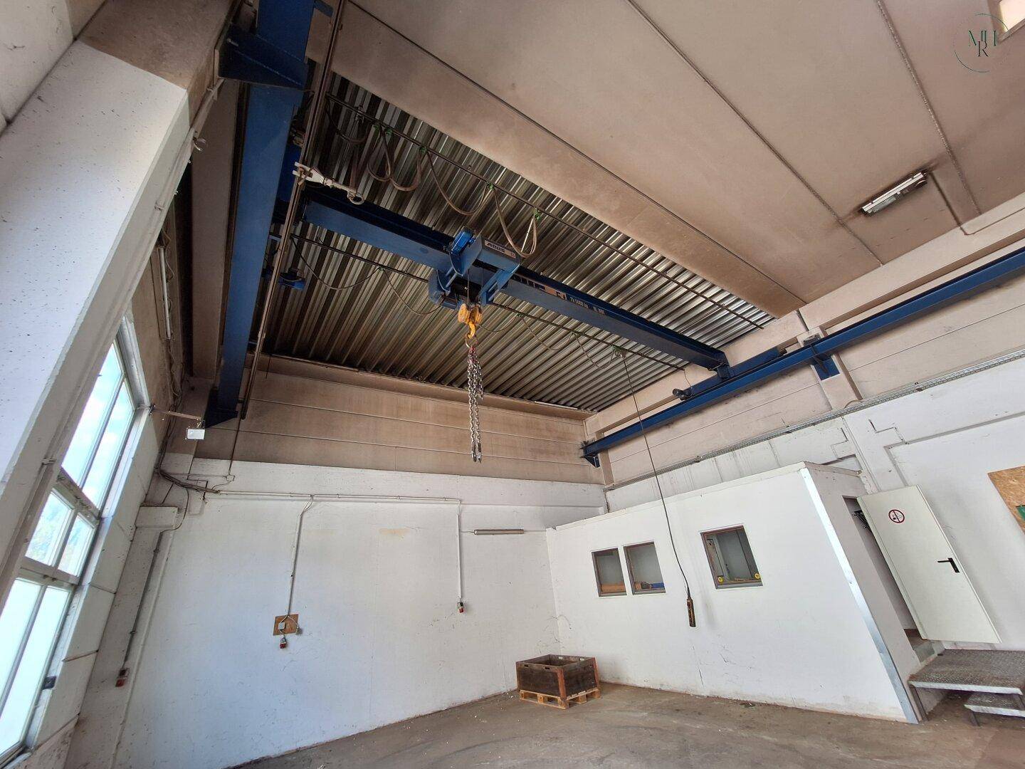 Blick auf den Laufkran und die hohen Decken der Halle, mit großen Fenstern für viel Tageslicht.