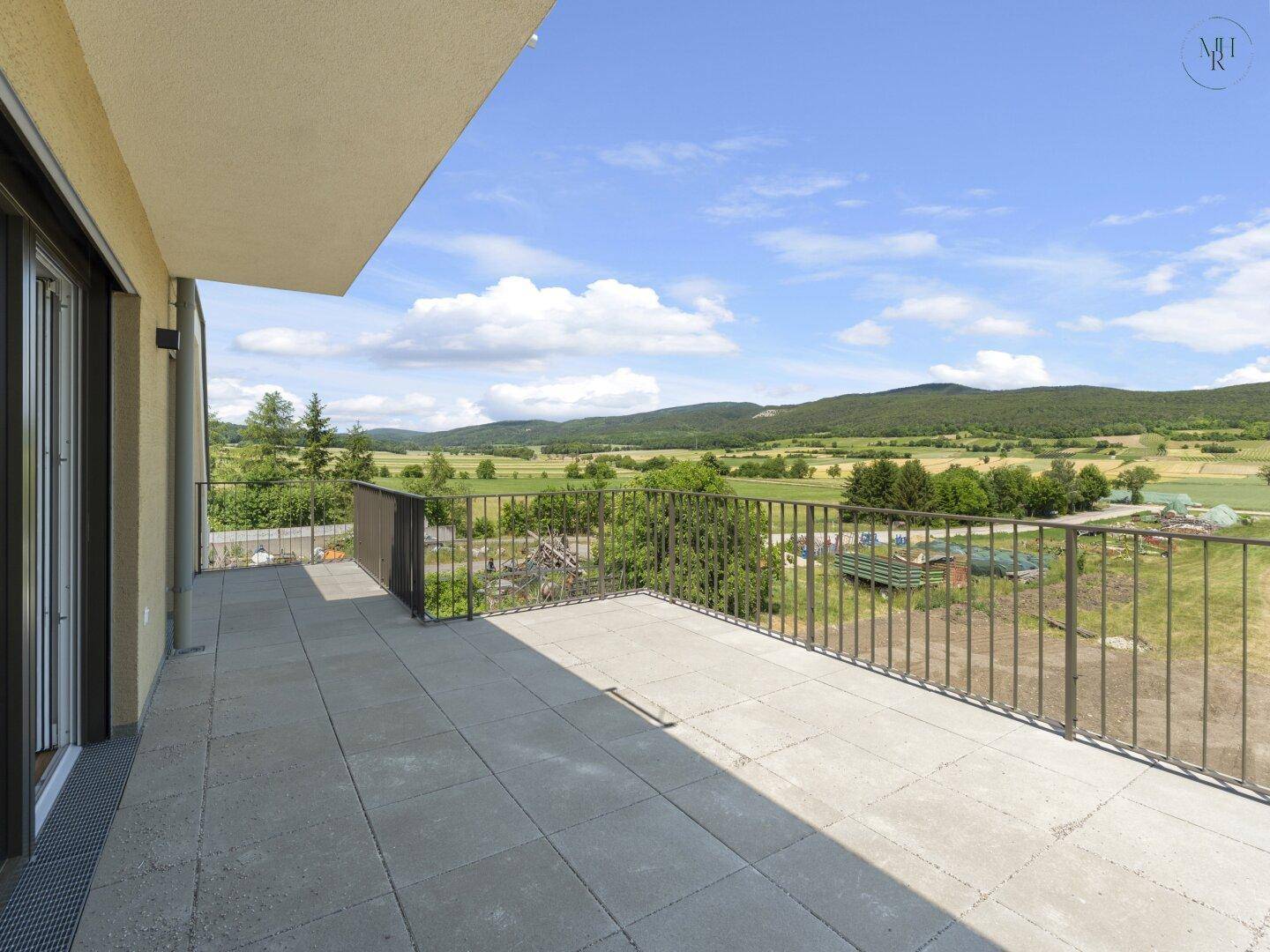 Geräumige Außenterrasse mit Metallgeländer und Panoramablick auf die umliegende Landschaft.