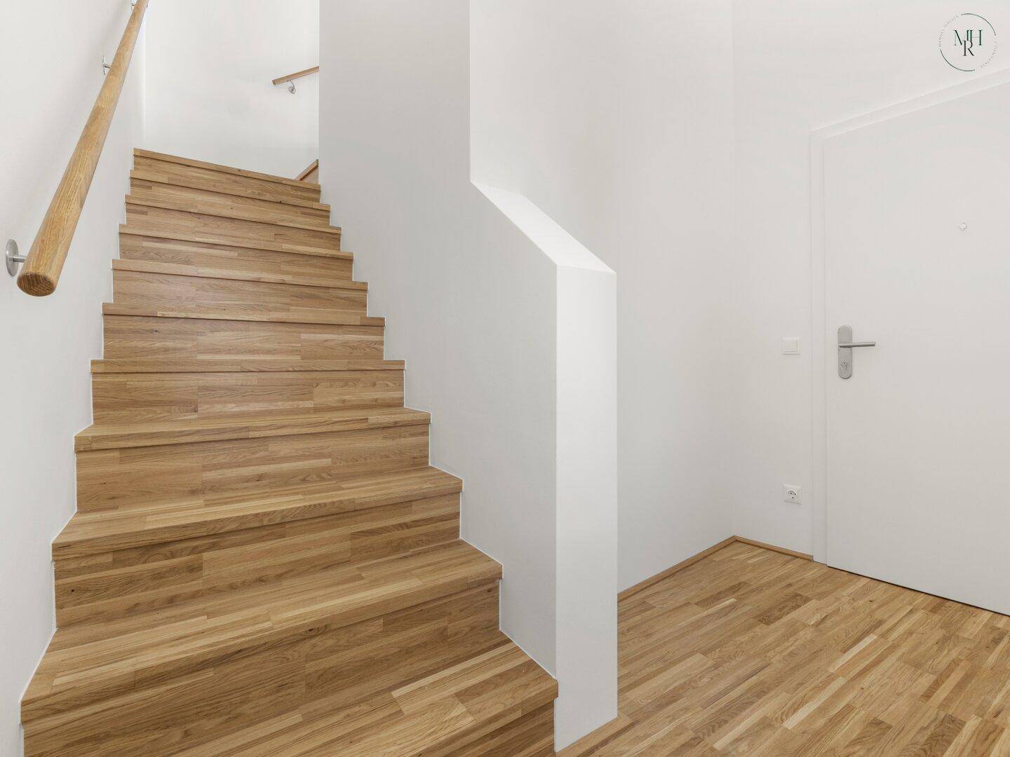 Helle Holztreppe mit schlichtem Geländer, die verschiedene Ebenen des Hauses verbindet.