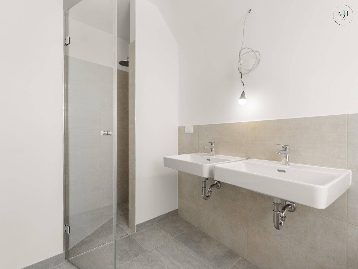Helles Badezimmer mit Doppelwaschbecken und einer modernen begehbaren Dusche mit Glasabtrennung.