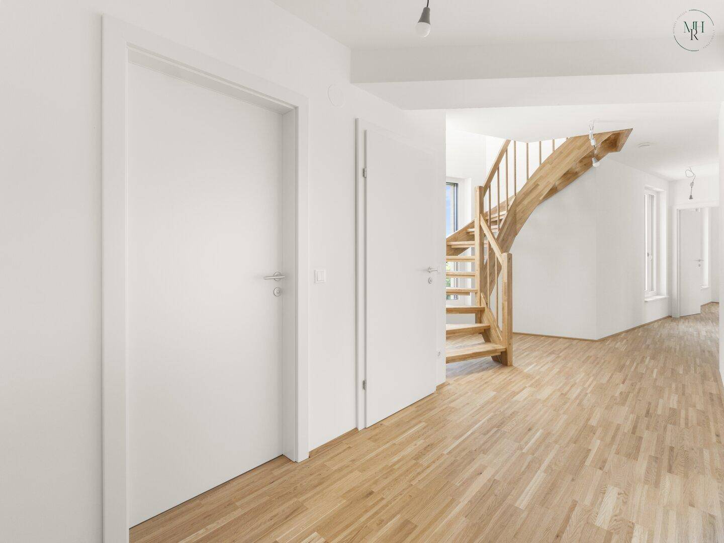Heller Flur mit Holztreppe und Holzboden, der zu den oberen Etagen führt.
